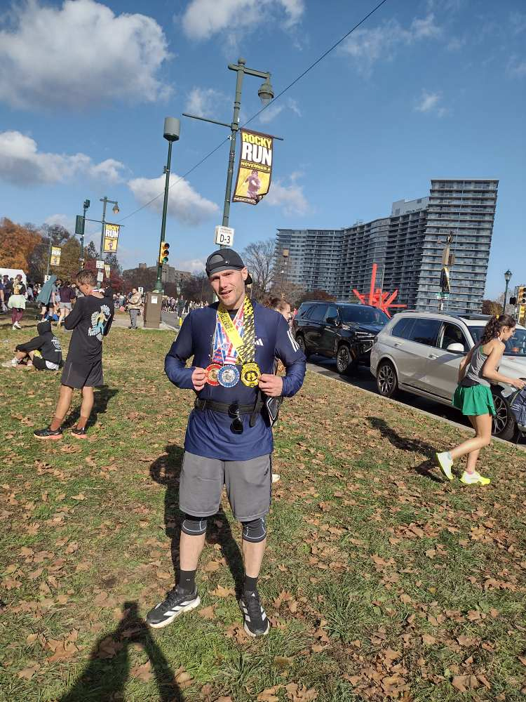 Man wearing running gear holding multiple race medals after completing a half marathon event