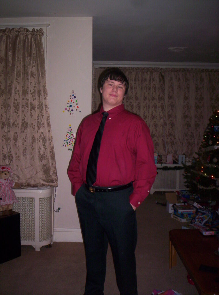 Overweight man in red dress shirt and tie standing indoors, before weight loss transformation